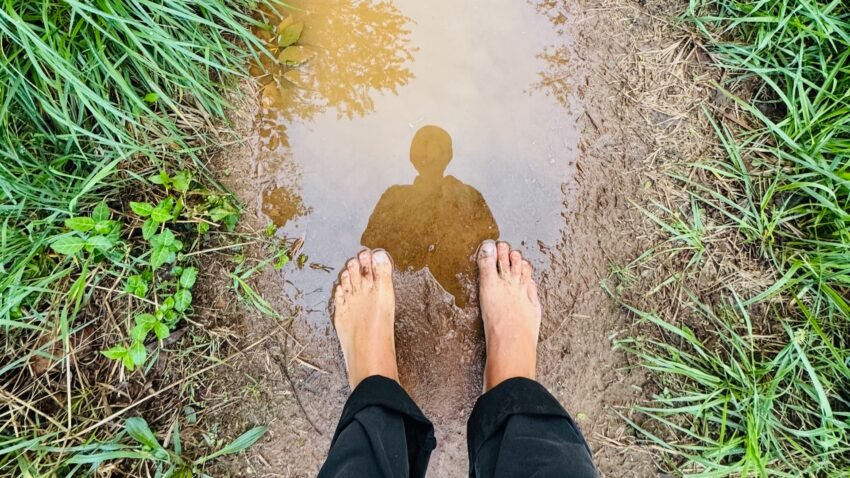 Barefoot reflection in a muddy path symbolizing healing and self-discovery
